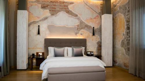 a bedroom with a large bed and a brick wall at Cartesiano Boutique & Wellness Hotel in Puebla