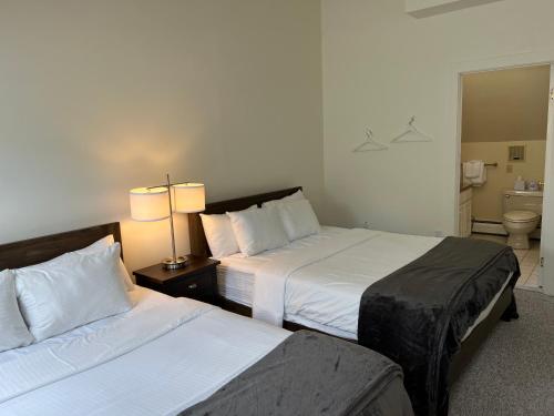a hotel room with two beds and a bathroom at The Nutmeg Vermont in Wilmington