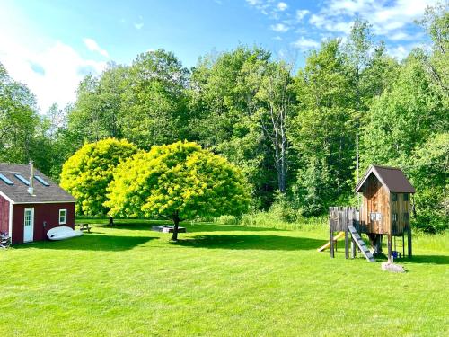 a park with a playground and a house and a tree at The Nutmeg Vermont in Wilmington