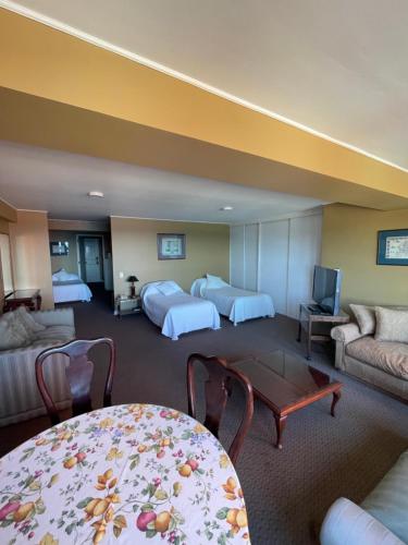 a hotel room with two beds and a table at Hotel Apart Colón in Puerto Montt