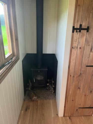 a hallway with a stove in a room with a door at Honeysuckle Shepherd's Hut in Northallerton
