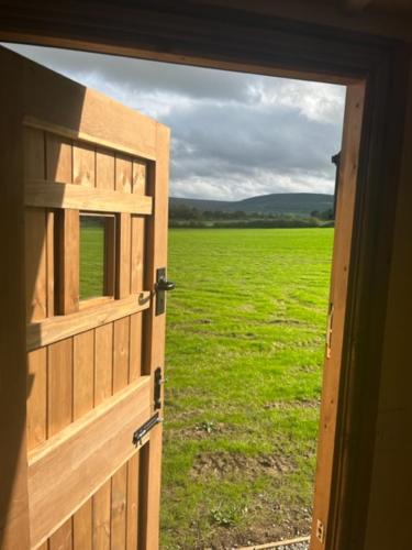 an open door looking out at a field of grass at Honeysuckle Shepherd's Hut in Northallerton