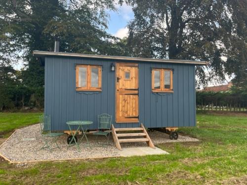 a blue tiny house sitting in a yard at Honeysuckle Shepherd's Hut in Northallerton
