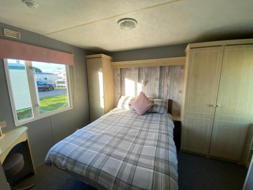 a bedroom with a bed with a pink pillow on it at Seaview 190 - Ingoldmells - Close to beach and Fantasy Island in Ingoldmells