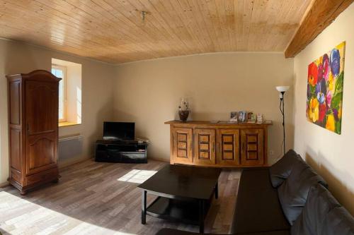 un soggiorno con divano e soffitto in legno di Le hameau du Maissubert 