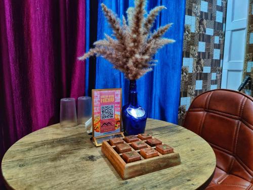 a table with a bottle of wine and a box of chocolate at Gadegal Homestay Narkanda - Rooms & Pahadi Café in Shimla