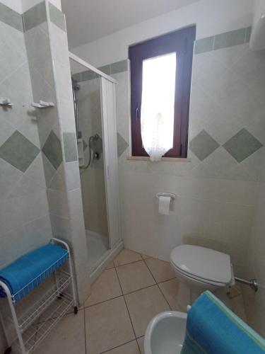 a bathroom with a toilet and a shower and a window at Nuova Valmar Turagri 34-35 in Costa Rei