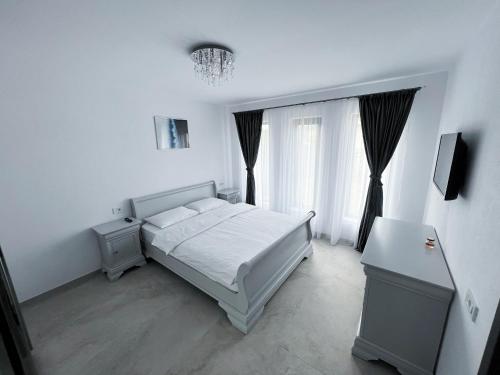 a white bedroom with a bed and a window at Casa Andreea in Curtea de Argeş