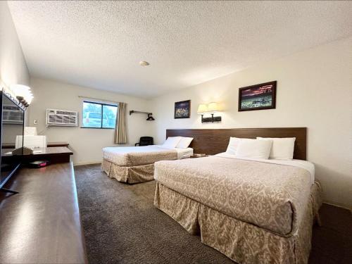 een hotelkamer met 2 bedden en een flatscreen-tv bij Homestead Inn in Wolf Point