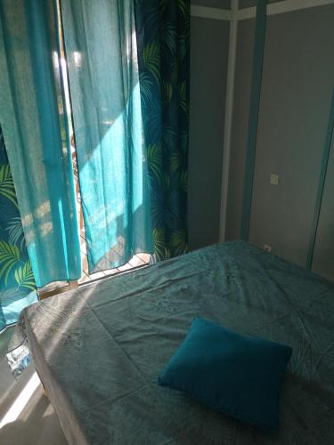a bedroom with a bed with a window with blue curtains at CHALET LOU PADER in Vézac