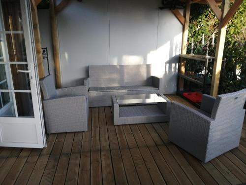 un patio con sillas de mimbre y una mesa en una terraza. en CHALET LOU PADER, en Vézac