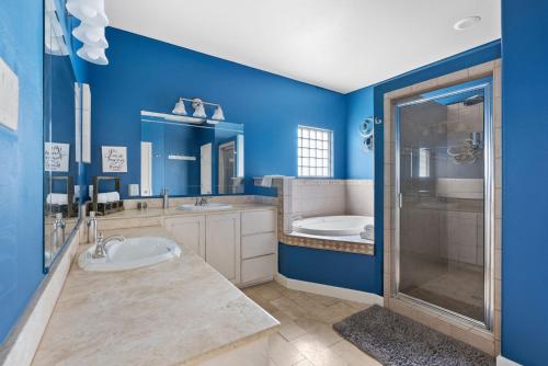 a blue bathroom with a tub and a sink and a shower at Brand New Lake Travis Estate - Awesome Pool in Austin