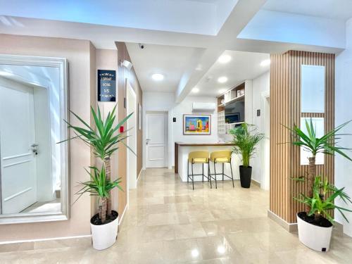 a living room with two potted plants and a kitchen at Comfort Apartments Pasha in Budva