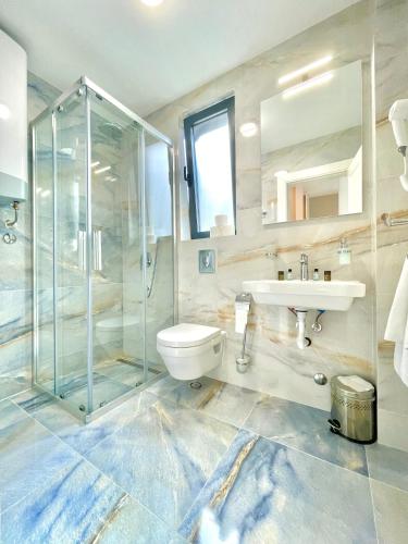 a bathroom with a shower and a toilet and a sink at Comfort Apartments Pasha in Budva