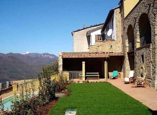 a large stone house with a yard of green grass at Palazzo D'arcato by PosarelliVillas in Lugliano