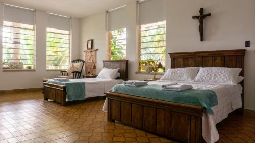 a bedroom with two beds and a cross on the wall at Finca San José Hotel Boutique in San Antonio del Tequendama