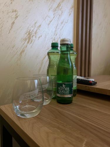 two green bottles and a glass on a wooden table at Villa Potôň 2023 in Horná Potôň