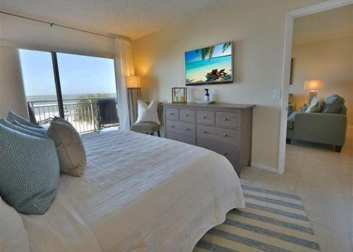 a bedroom with a large bed and a balcony at Beachfront Madeira Norte in St Pete Beach