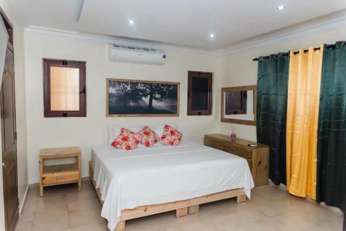 a bedroom with a white bed with red pillows at Verde Bonavita in Santiago de los Caballeros