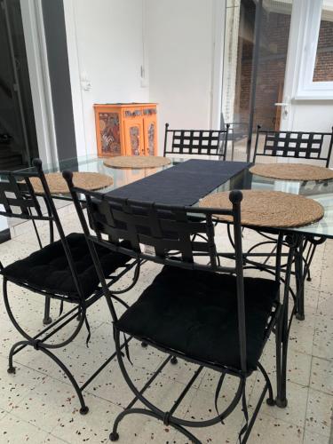 stół z 4 krzesłami i stół z czarnym stołem w obiekcie GITE Le tapis vert - Guise w mieście Guise