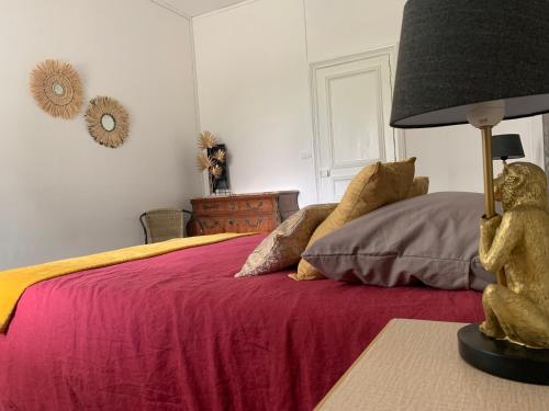 um quarto com uma cama com um cobertor vermelho e um candeeiro em GITE Le tapis vert - Guise em Guise