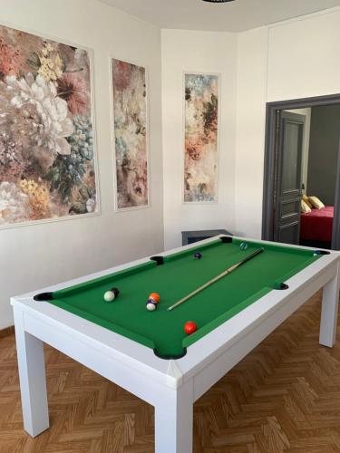 uma mesa de bilhar com bolas num quarto com pinturas em GITE Le tapis vert - Guise em Guise