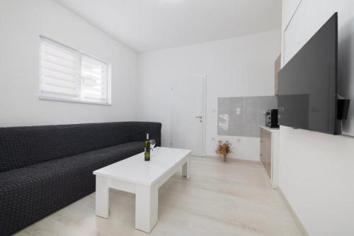 a living room with a black couch and a white table at Apartman BARIŠIĆ 1 in Kupres