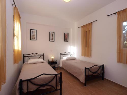 two beds in a room with white walls and windows at villa Nefeli in Lambiní