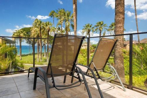 two chairs on a balcony with palm trees and the ocean at WAILEA ELUA, #1104 condo in Wailea