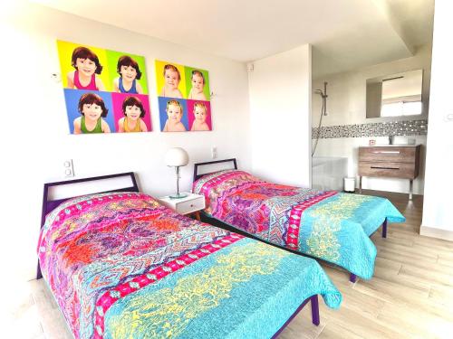 - 2 lits dans une chambre avec des affiches sur le mur dans l'établissement Détente Côte d'azur, piscine et spa privatifs, à Menton