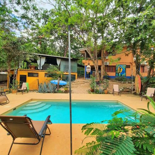 a swimming pool with a chair and a house at Casa Pura Vida Surf Hostel - Tamarindo Costa Rica in Tamarindo