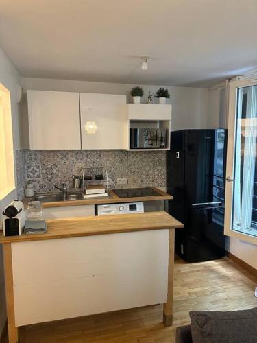 une cuisine avec des armoires blanches et un comptoir dans l'établissement Joli studio- quartier Montmartre, à Paris