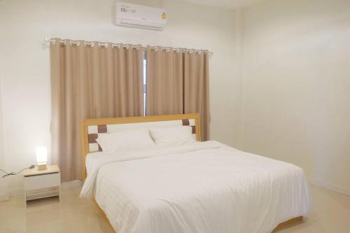 um quarto com uma cama branca e uma janela em วิลล่าสุดชีค ในเชียงราย em Ban Pa Faek