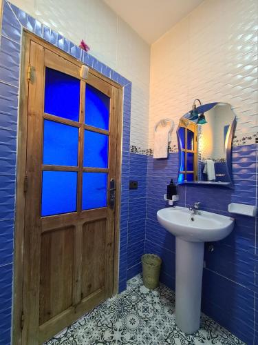 a bathroom with a wooden door and a sink at Casa Blue Star in Chefchaouen