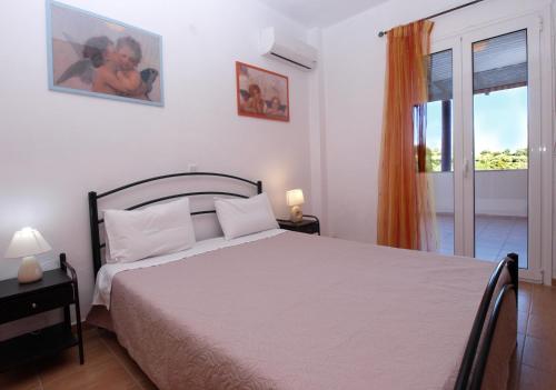 a bedroom with a white bed and a window at villa Nefeli in Lambiní