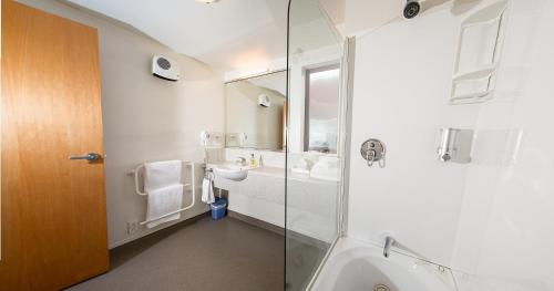 a bathroom with a glass shower and a sink at Alhambra Oaks Motor Lodge in Dunedin
