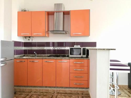 a kitchen with orange cabinets and a microwave at Appart Clim Wifi 700m de la Plage in Saidia 