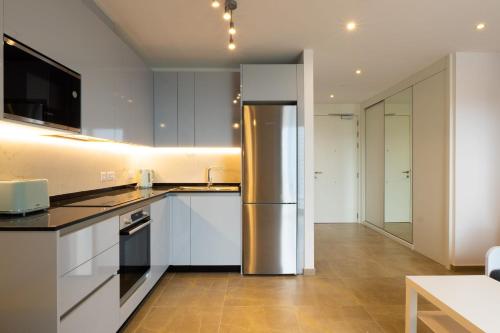 a kitchen with white cabinets and a stainless steel refrigerator at E1 Rock View Studio9 -Hosted by Sweetstay in Gibraltar