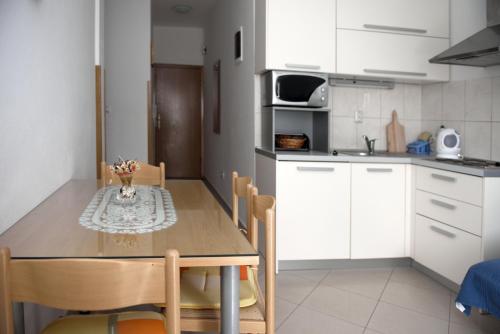a kitchen with white cabinets and a wooden table with chairs at Villa Srima in Vodice