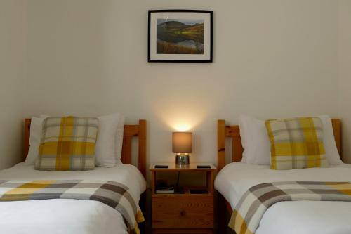 a bedroom with two beds and a table with a lamp at Black Sheep Bunkhouse in Fort William