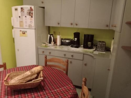une cuisine avec une table, un réfrigérateur et une table avec un chiffon de table dans l'établissement Chambre chez l'habitant, à Pierrelatte