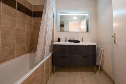 La salle de bains est pourvue d'un lavabo, d'une baignoire et d'un miroir. dans l'établissement Cocon cosy 3 pers, Colomiers - So Cozy, à Colomiers