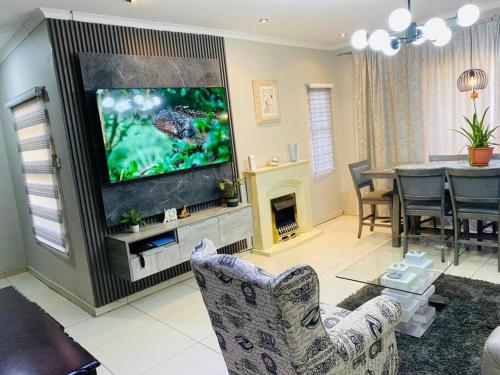 ein Wohnzimmer mit einem TV und einem Esszimmer in der Unterkunft Central Gabs Oasis: 2BR-Retreat in Gaborone