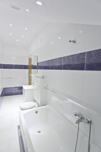 a white bathroom with a tub and a toilet at Hotel Martini Zagreb Hotel and Restaurant in Sesvete