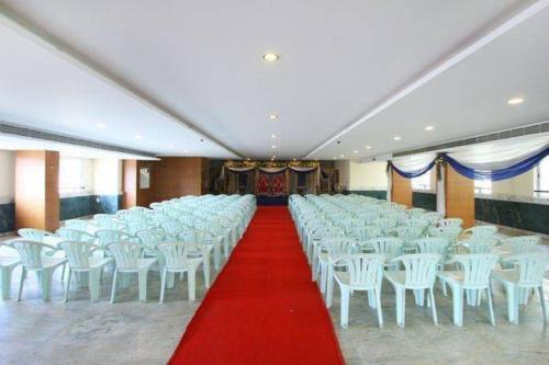 Großes Zimmer mit weißen Stühlen und einem roten Teppich in der Unterkunft Suvarna Residency in Mysore