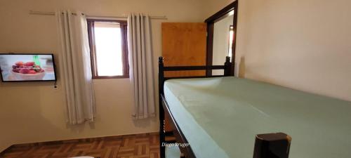 um pequeno quarto com uma cama e uma janela em Casa perto das Cataratas Seu lar para quatro em Foz do Iguaçu