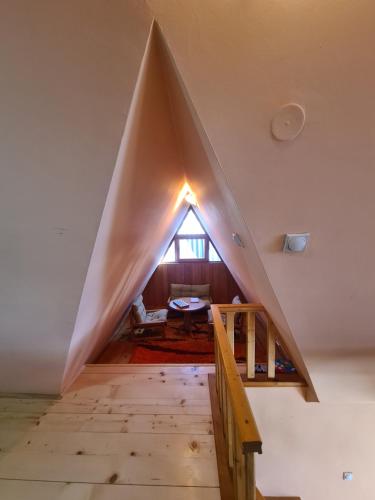 a pyramid shaped room with a staircase and a window at Vikendica Nina in Mitrovac