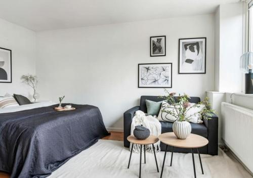 a bedroom with a bed and two tables and a couch at Cousy and convenient in Västerås