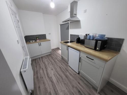 a kitchen with white cabinets and a wooden counter top at Nottingham Forest Rd, Short Stays in Nottingham