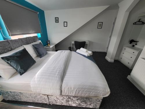 a bedroom with a large white bed with blue walls at Nottingham Forest Rd, Short Stays in Nottingham